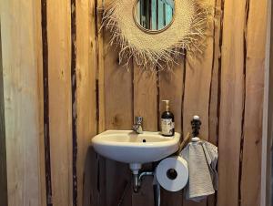 a bathroom with a sink and a mirror on a wooden wall at Abula puhkemaja 2 in Abula