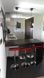una cocina con encimera negra y taburetes rojos en TOURON Nº1, en Carballedo