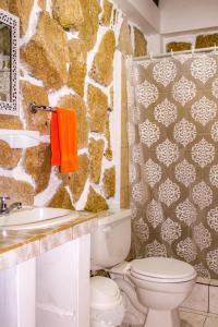 a bathroom with a toilet and a stone wall at HANGA ROA HOTEL in Montañita