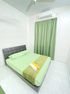 a bedroom with a bed with green sheets and a window at AL Homestay Pendang in Pendang