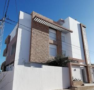 a white building with a brick wall at S+1 vue mer climatisé in Chott Meriem