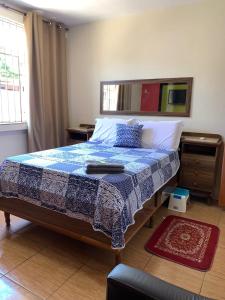1 dormitorio con 1 cama con manta azul y blanca en Quartos Em Casa Caxias - Pousada Paraíso en Duque de Caxias