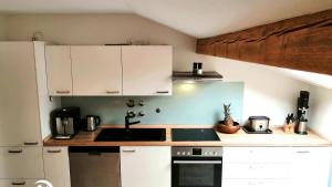 a kitchen with white cabinets and a stove top oven at FeWo Löwenzahn, Oberstaufen/Wiedemannsdorf in Oberstaufen