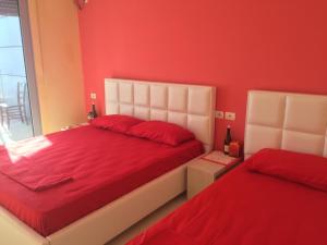 發羅拉的住宿－LUX SEAVIEW APARTMENT，卧室设有红色的墙壁和白色的床。