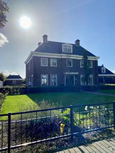 a large house with a fence in front of it at De Parel B&B in Breezand