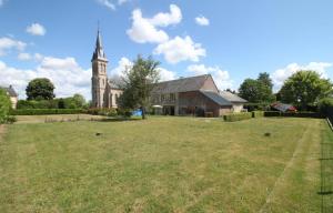 a church with a grassy yard in front of a building at La Meunière 2 in Montmerrei