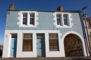 an old stone house with an archway in front of it at Ridley's Place modern one-bedroom seaside apartment in Eyemouth