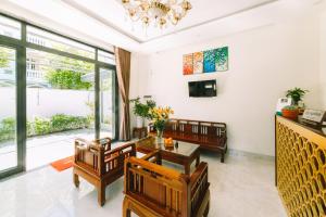 uma sala de estar com uma mesa e cadeiras e um lustre em The Sunshine Hoi An Villa em Hoi An