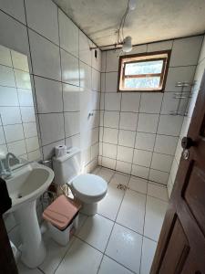 a bathroom with a toilet and a sink and a window at Casa Tamboril in Sao Jorge