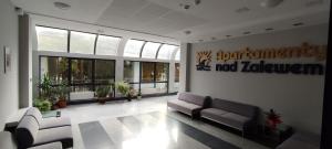 a lobby with couches and plants in a building at Apartament Nad Zalewem Zegrzyńskim in Serock