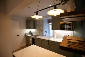 a kitchen with green cabinets and a sink and lights at Luxurious one-bedroom seaside apartment in Eyemouth