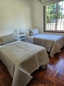 two beds sitting next to each other in a room at Casa DELUXE MALBEC , Barrio Privado, con cochera doble, jardín y churrasquera in Mendoza