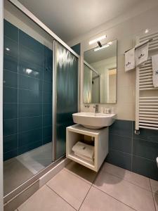 uma casa de banho com um lavatório, um chuveiro e um espelho. em Hotel Albatros em Lido di Jesolo