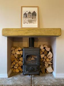 - un poêle à bois dans une chambre avec des bûches dans l'établissement 4 bedroom coastal cottage with walled garden, à Embleton