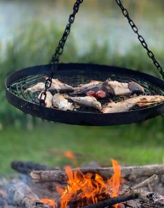 a grill over a fire with meat and vegetables at Leśniczówka Szeroki Bór in Szeroki Bór