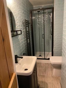 La salle de bains est pourvue d'un lavabo et d'une douche. dans l'établissement 4 bedroom coastal cottage with walled garden, à Embleton