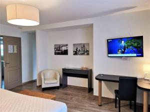 um quarto com uma cama e uma secretária e uma televisão na parede em Chambres d'hôtes GIDY em Gidy