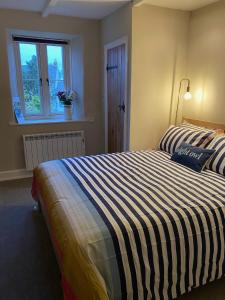 - une chambre avec un grand lit et une couverture rayée dans l'établissement 4 bedroom coastal cottage with walled garden, à Embleton