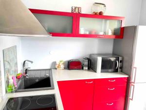 a small kitchen with red cabinets and a microwave at Quiet and comfortable apartment with parking for a nice stay for one,two or a couple with a child in Tallinn