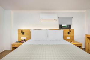 a bedroom with a large white bed with white pillows at AlexMare Hotel Fourka in Skala Fourkas