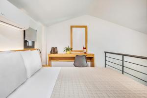 a bedroom with a bed and a desk with a mirror at AlexMare Hotel Fourka in Skala Fourkas