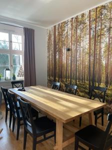 a dining room with a wooden table and trees mural at Leśniczówka Szeroki Bór in Szeroki Bór