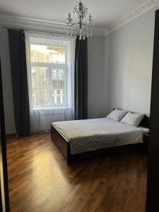 Schlafzimmer mit einem Bett und einem Fenster in der Unterkunft APARTMENT ON CENTRE LVIV in Lwiw