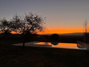 una piscina con puesta de sol en el fondo en Altos del Espinillo - Casa de Montaña in 