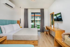 a hotel room with a bed and a desk and a window at AlexMare Hotel Fourka in Skala Fourkas