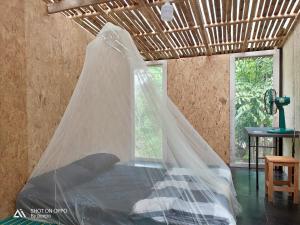 uma cama com uma rede mosquiteira num quarto em แม่ไพโฮมสเตย์ ล่องแพกอนโดล่า 