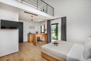 a bedroom with a bed and a desk with a television at AlexMare Hotel Fourka in Skála Foúrkas