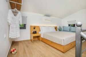 a bedroom with a bed and a dress hanging on a wall at AlexMare Hotel Fourka in Skala Fourkas