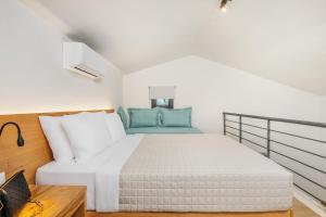 a bedroom with a white bed with blue pillows at AlexMare Hotel Fourka in Skala Fourkas