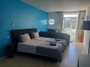 a bedroom with a bed with a blue wall at Quartos do Seixe - Azul in Odeceixe