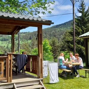 un gruppo di persone seduti a un tavolo su un ponte di Chalet et mobil homes dans la montagne au Camping les Sapins a Camurac