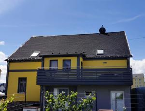 a yellow and black house with a balcony at Fewo Klöppel Auersbergblick in Eibenstock