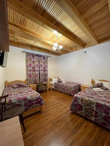 2 camas en una habitación con suelo de madera en Mutara Bukhara, en Bukhara