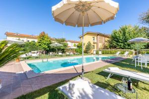 einen Pool mit Sonnenschirm, Tisch und Stühlen in der Unterkunft Villa Gabriella in Lucca