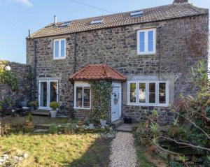 an old stone house with a white door at 4 bedroom coastal cottage with walled garden in Embleton