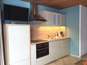 kuchnia z białymi szafkami i telewizorem na ścianie w obiekcie Appartement Fischer w mieście Sankt Johann in Tirol