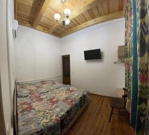ein Schlafzimmer mit einem Bett und einem TV an der Wand in der Unterkunft Mutara Bukhara in Buxoro