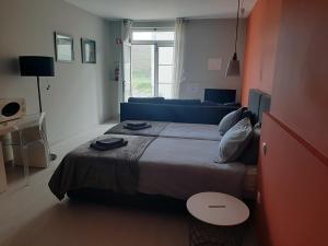 a bedroom with a large bed and a blue couch at Quartos Do Seixe - Laranja in Odeceixe