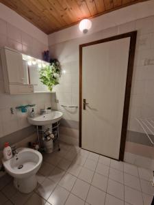 uma casa de banho com um WC, um lavatório e uma porta em Appartamento Latemar Predazzo em Predazzo