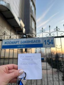 une personne tenant un morceau de papier avec une chaîne de clé dans l'établissement apartments Southern View, à Bishkek