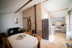 a kitchen and living room with a table and a refrigerator at Gite Le Figuier - La Roseraie du Val'ensoleillé in Valensole