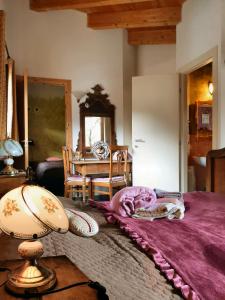 Un dormitorio con una cama con sábanas moradas y una mesa. en Villa Amaranta Room and Breakfast, en Edolo