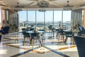 a dining room with tables and chairs and large windows at Miraclz Skyline Tower in Dubai