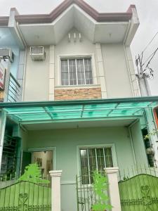 una casa verde y blanca con una valla en Townhouse Apartment near SM City Lucena, en Lucena