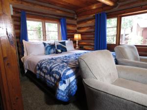 um quarto com uma cama e uma cadeira num chalé de madeira em Tall Pines Inn em Eureka Springs