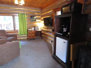 a living room with a couch and a tv in a log cabin at Tall Pines Inn in Eureka Springs